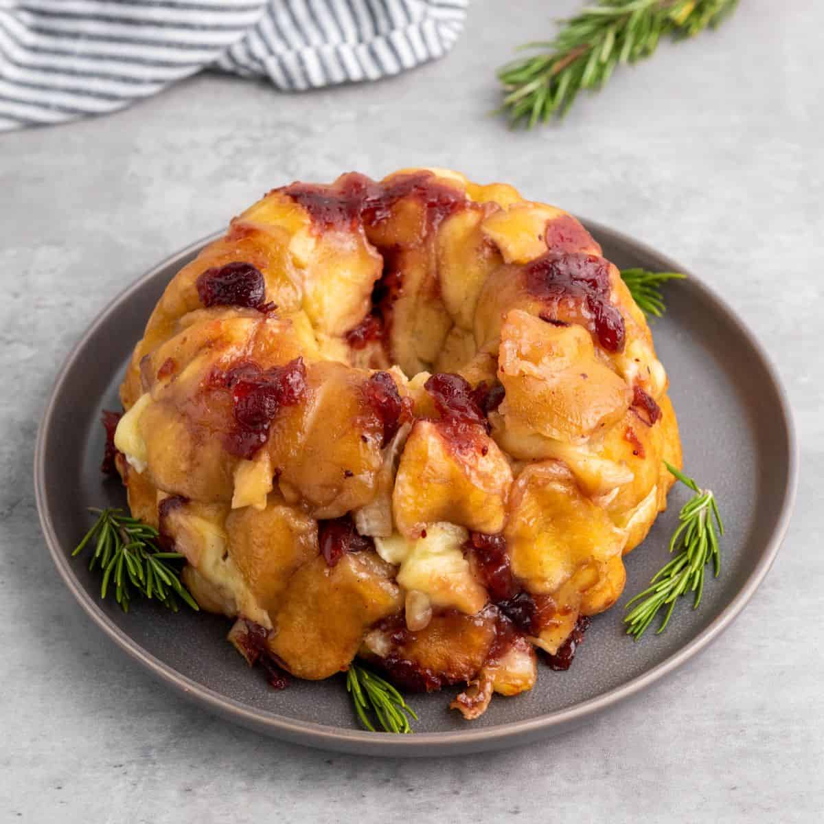 Mini pull-apart bread served on a plate with a cloth beside it.