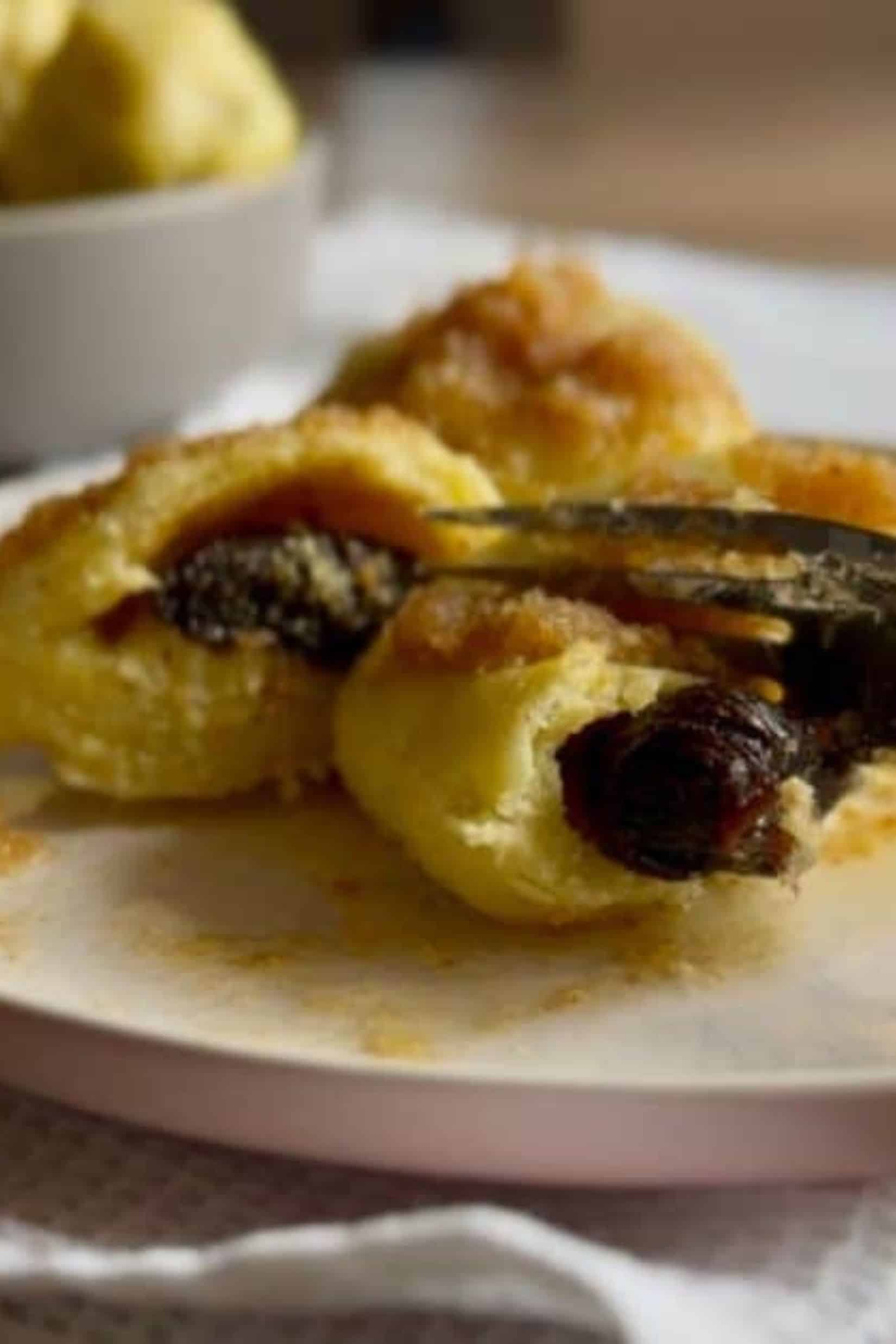 A fork slicing a traditional dumpling on a plate, revealing the filling inside.