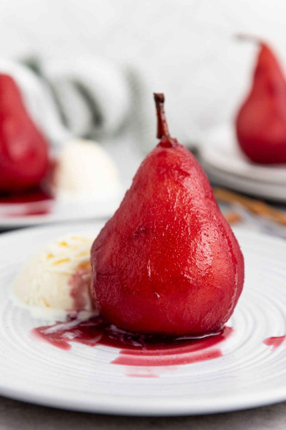 A single pear on a plate, served with a scoop of vanilla ice cream.