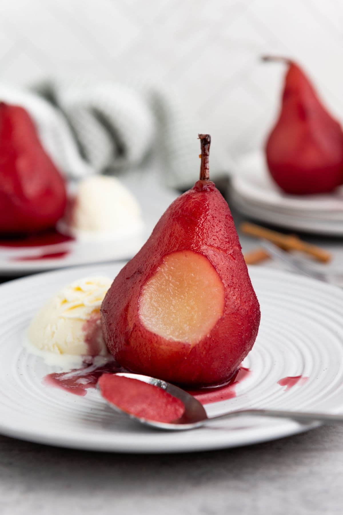 A single pear with a bite taken out of the center on a plate, served with a scoop of vanilla ice cream.