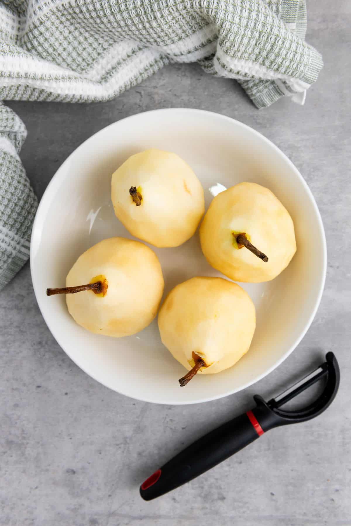 Four Bosc pears placed neatly in a bowl.