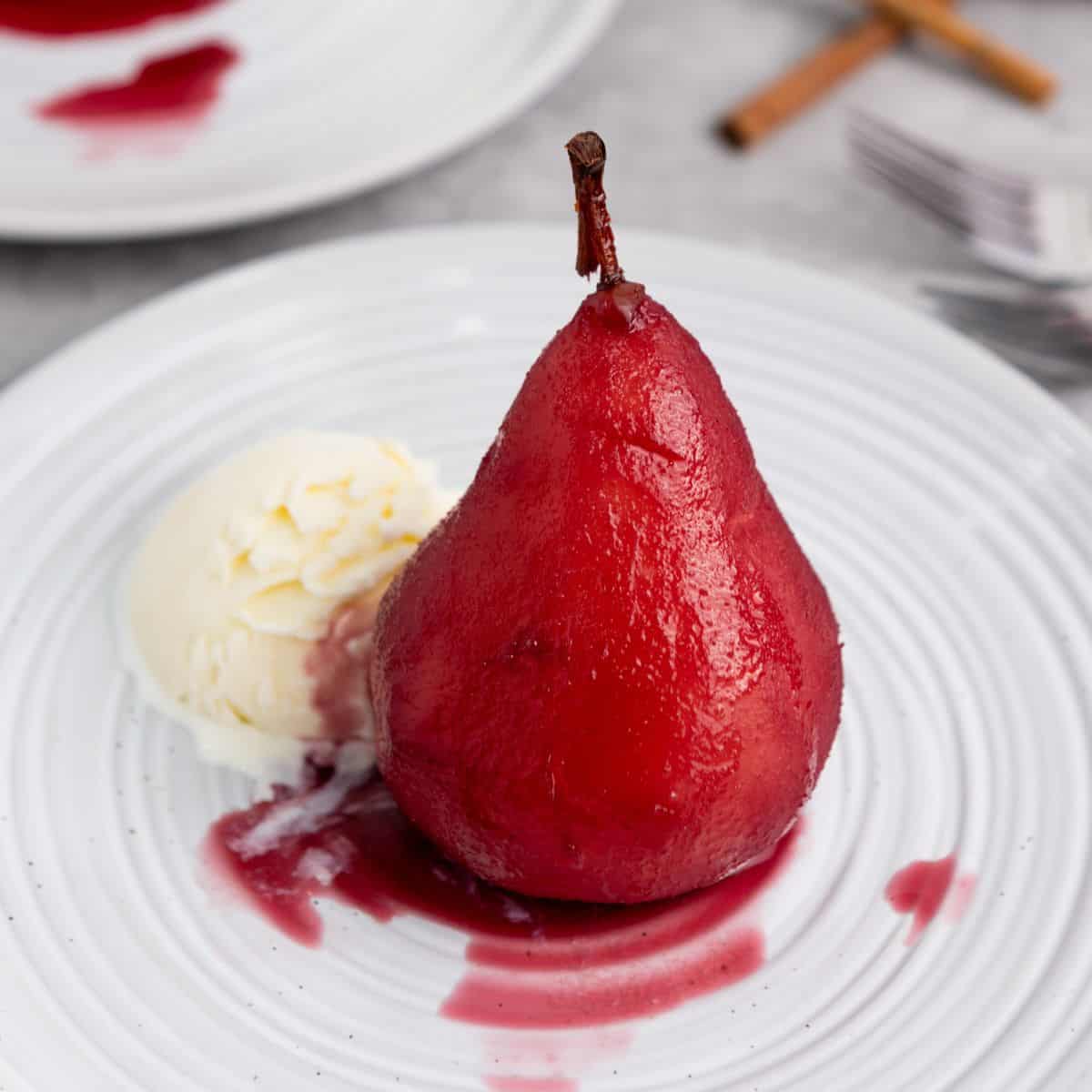 A single pear on a plate, served with a scoop of vanilla ice cream.