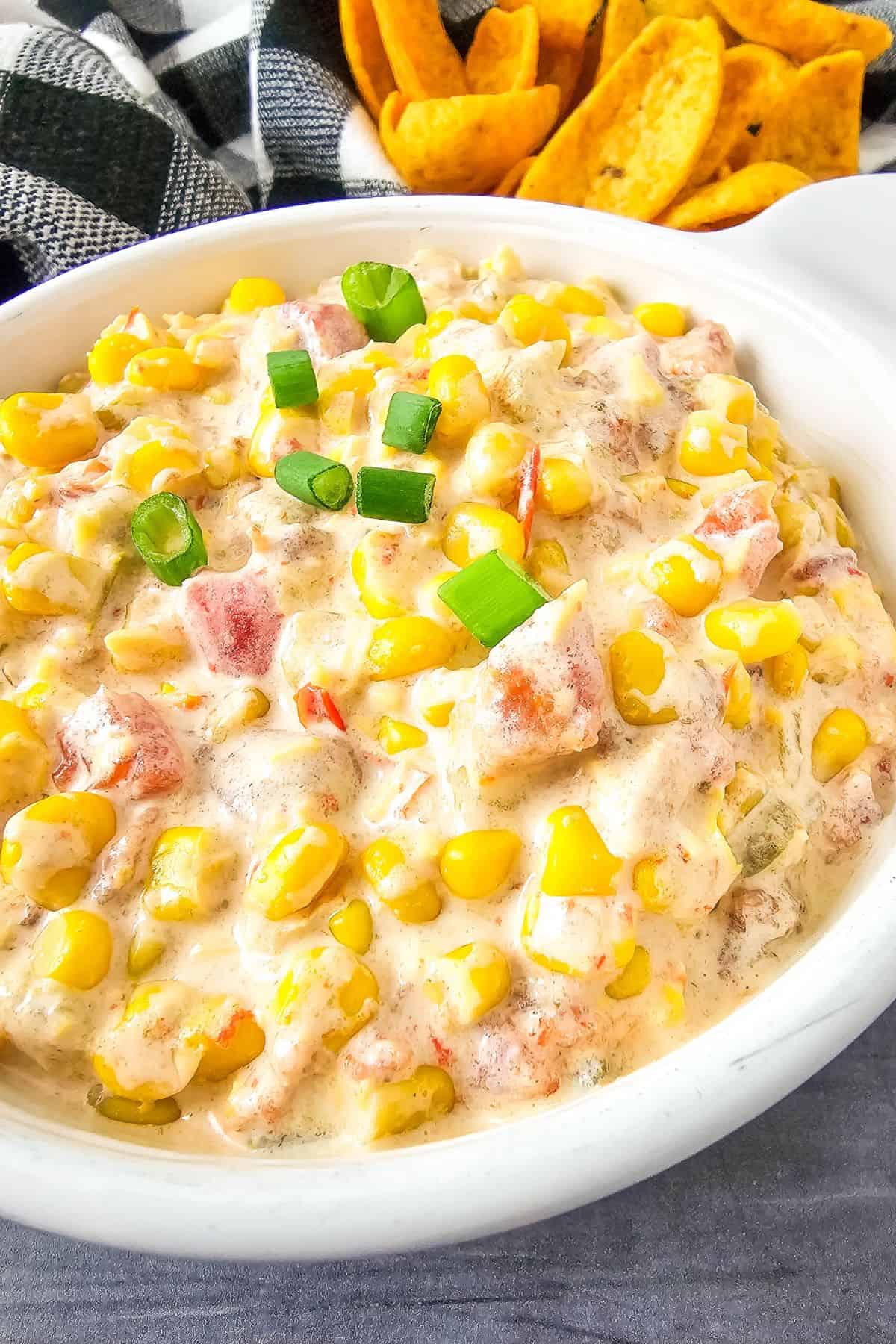 Close-up photo of creamy corn dip in a bowl, showing bits of corn and cheese mixed into the smooth, rich texture.