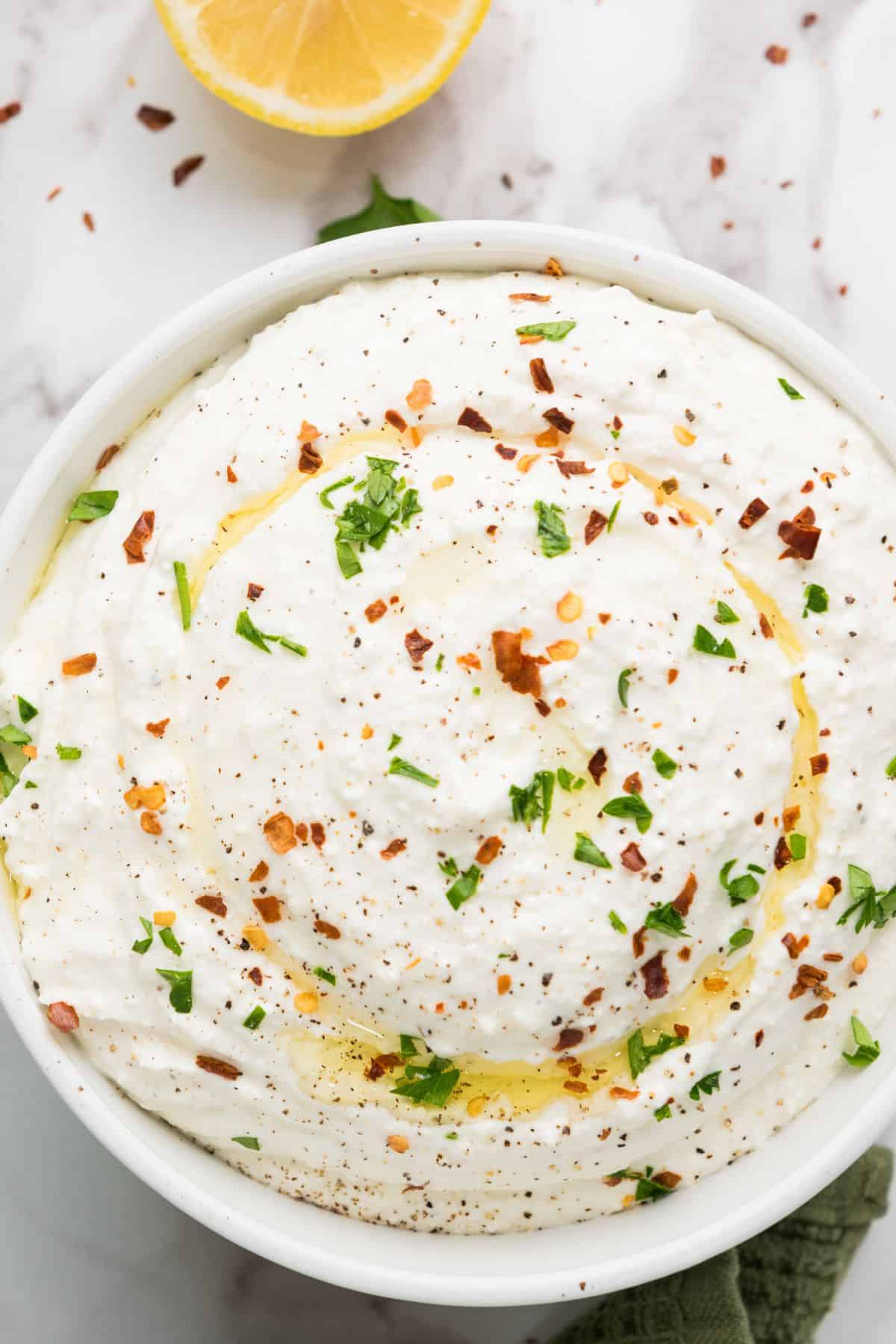 Zesty lemony feta dip served in a bowl, showing its creamy texture and crumbly feta bits.