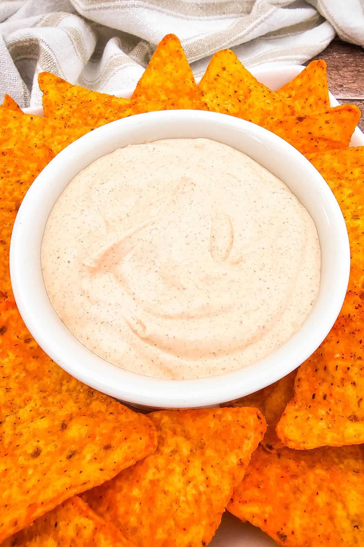 Bowl of taco ranch dip in the center surrounded by crunchy tortilla chips, showing its creamy texture and seasoned color.