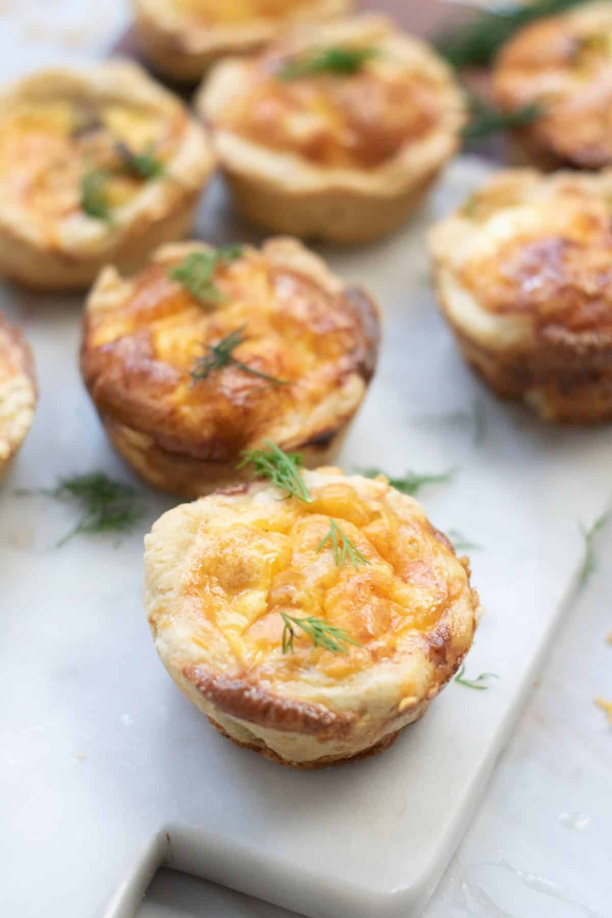Party-ready salmon quiche bites arranged on a marble board.