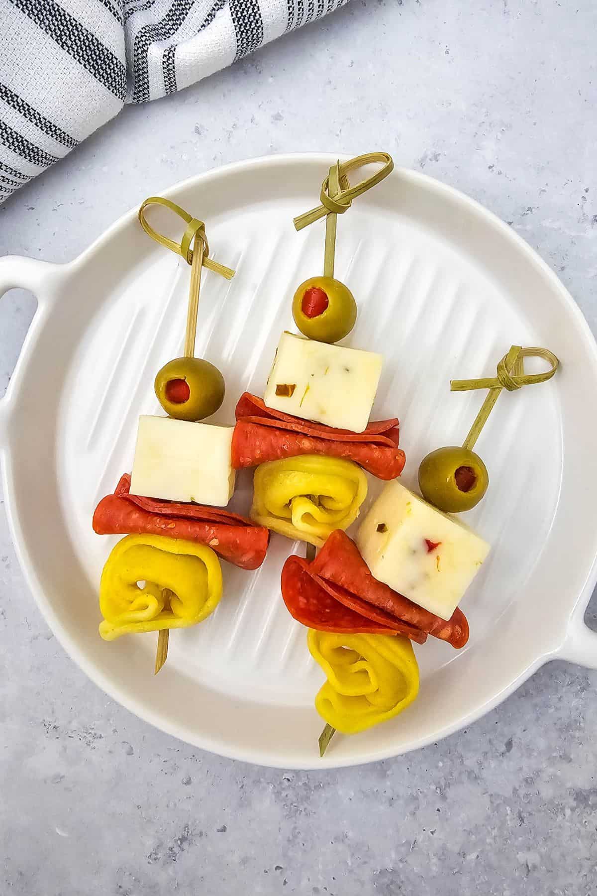 Tortellini skewers with pepperoni and olives arranged in a serving dish.