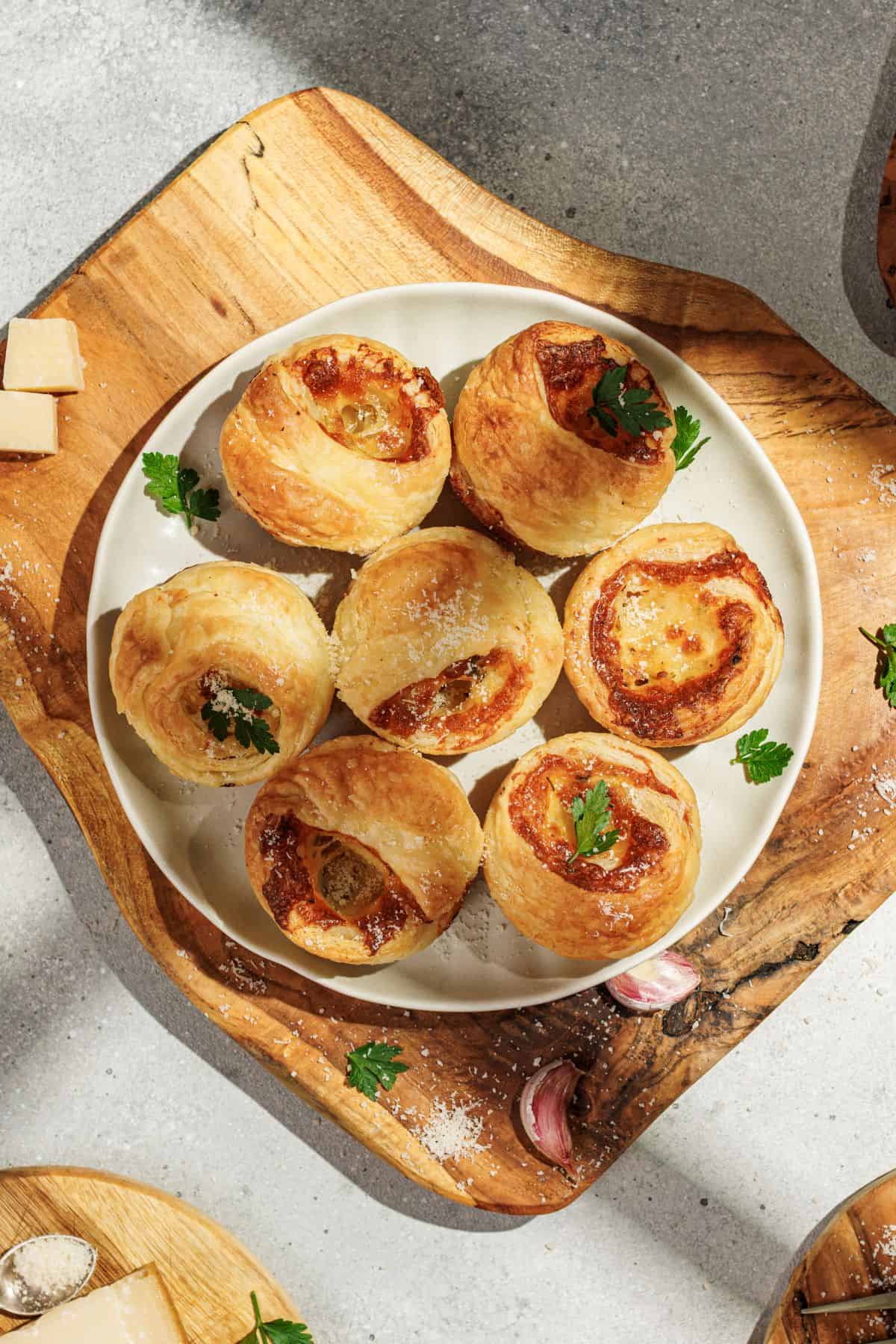 Cheesy garlic cruffins served on a plate with a wooden board underneath.