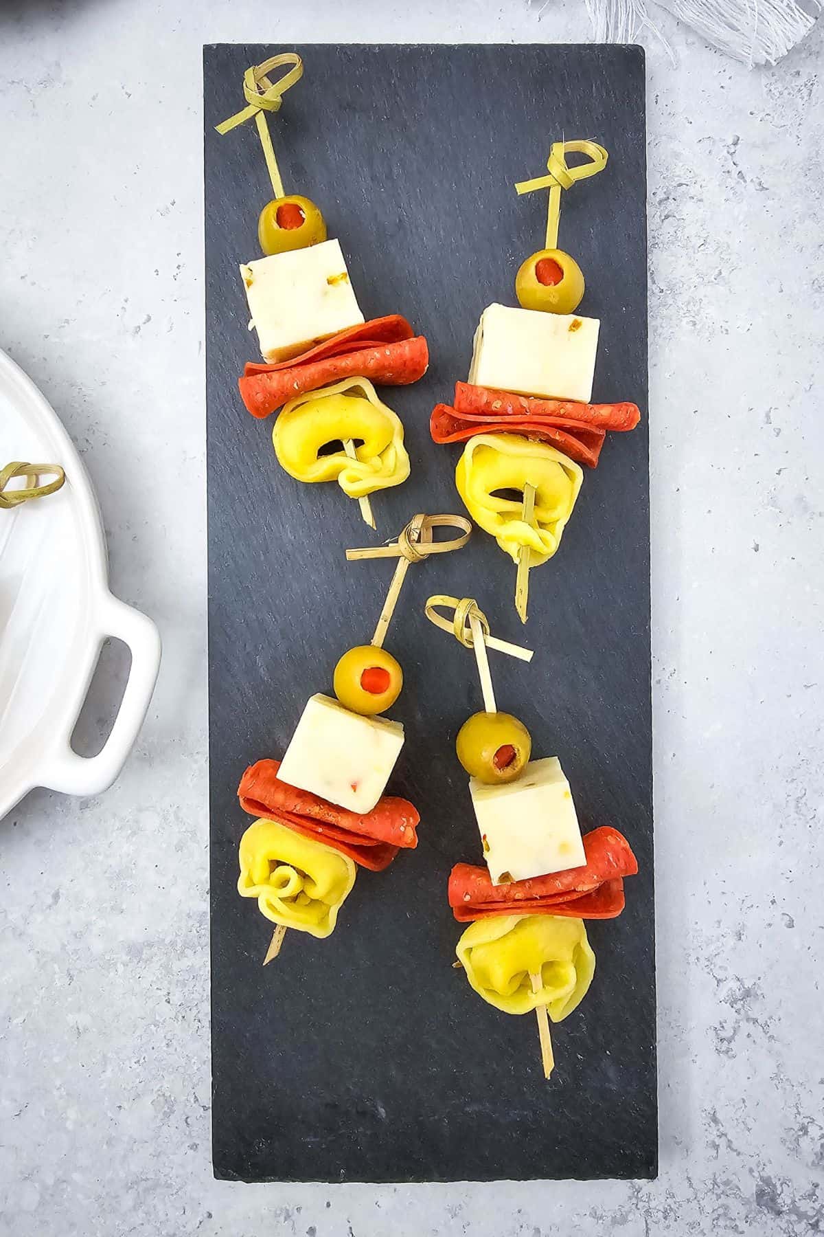 Tortellini skewers with pepperoni and olives arranged on a serving board.