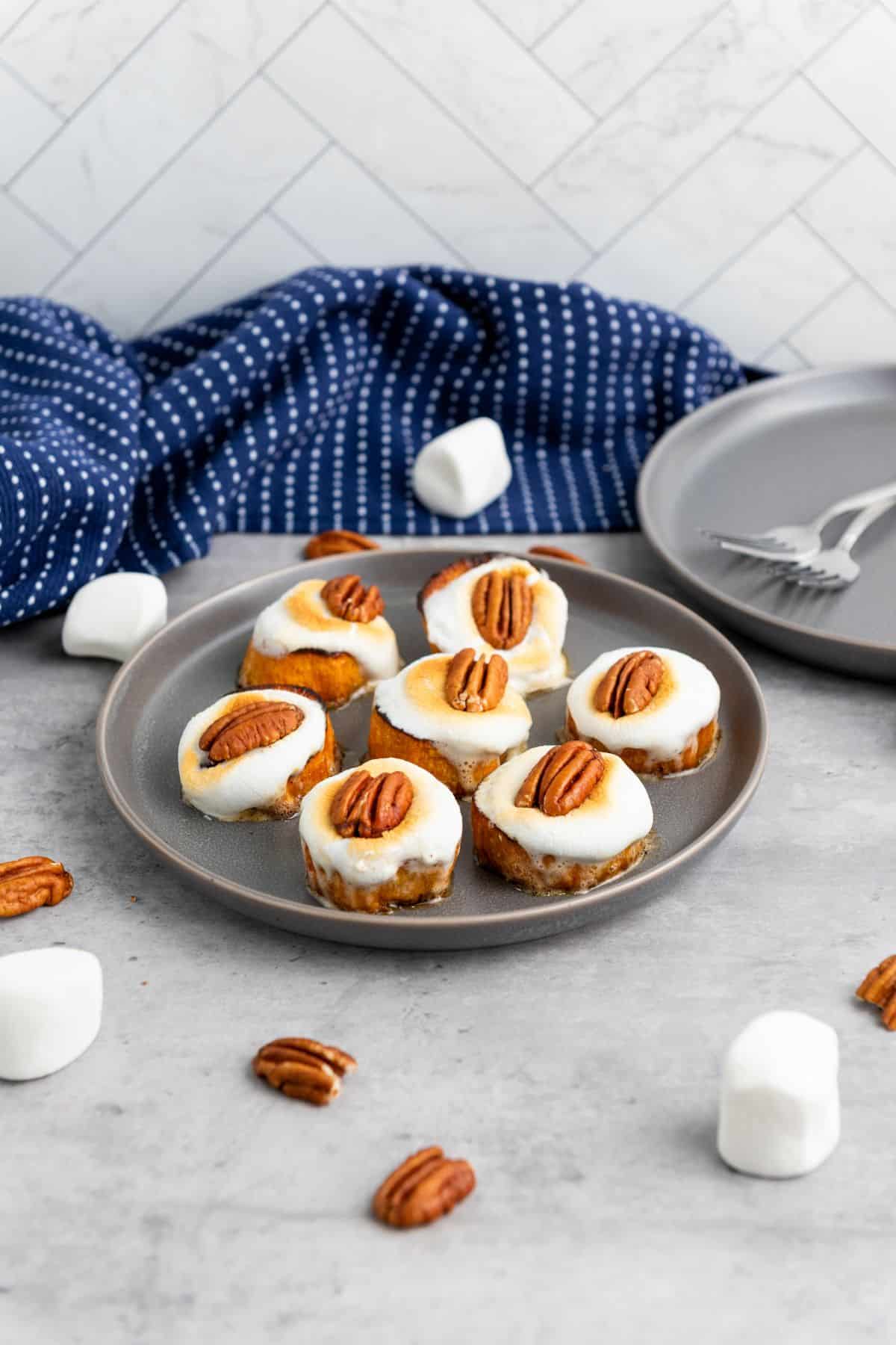 Baked sweet potato bites arranged on a plate, topped with marshmallows and pecans.