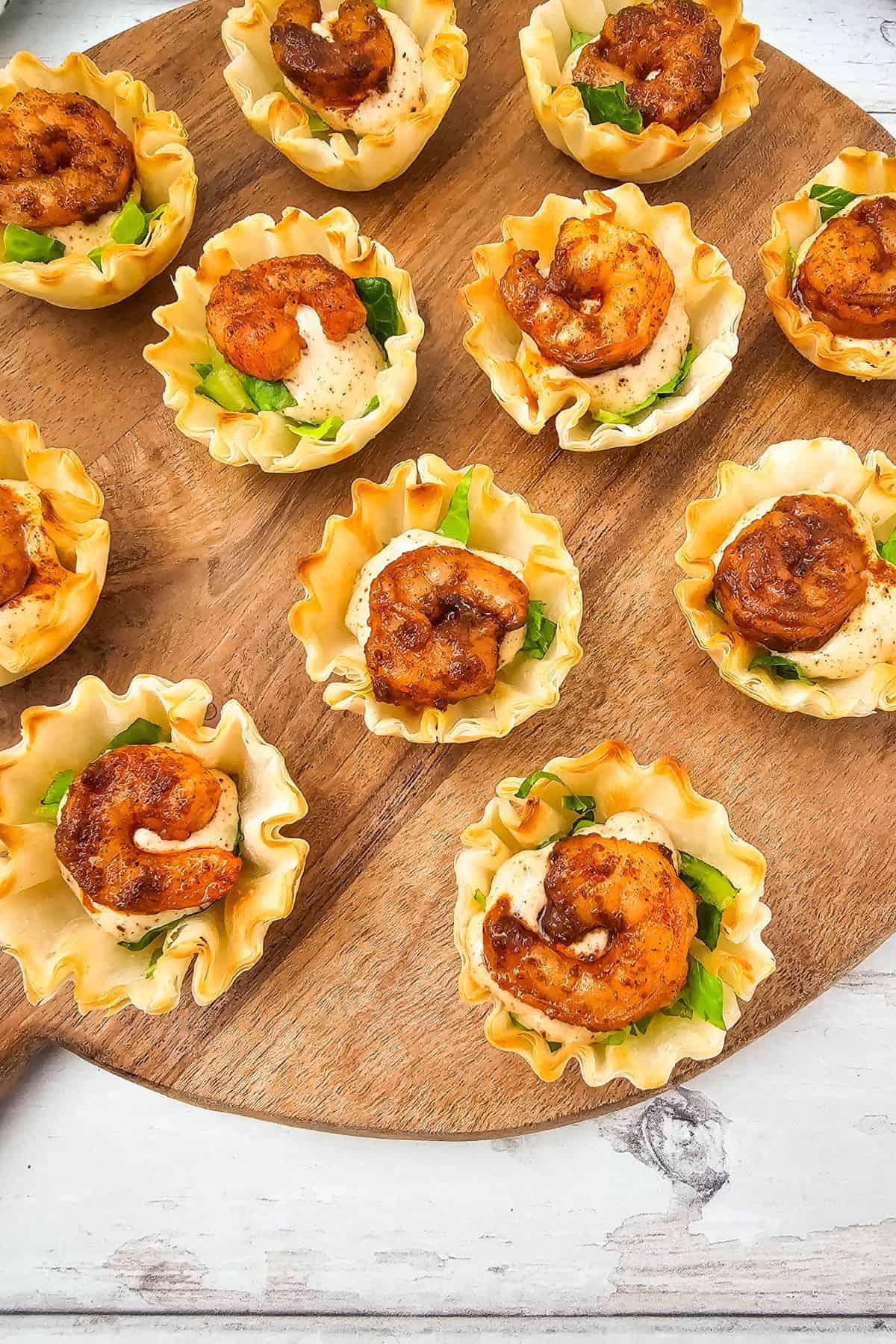 Chili lime shrimp cups arranged on a wooden serving board, ready to serve.