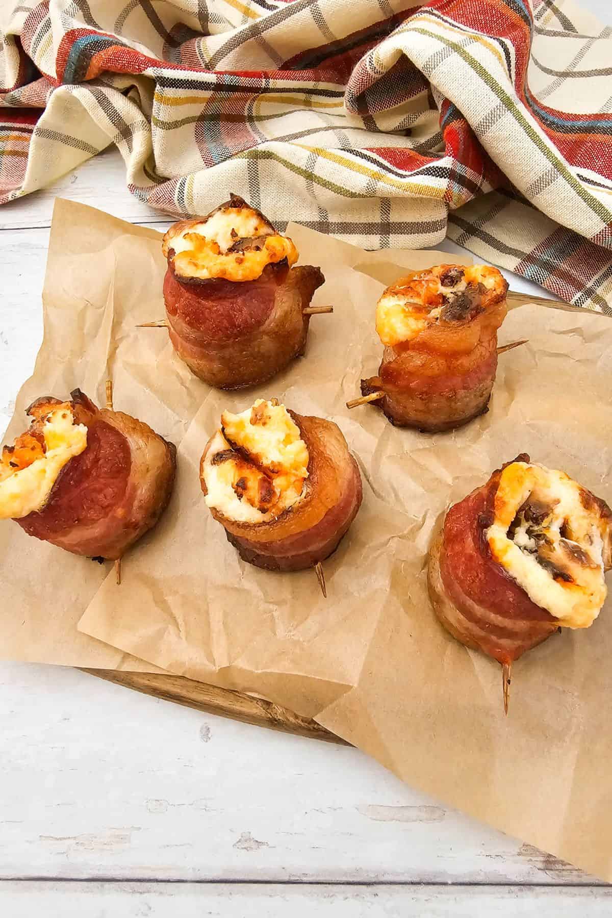 ir fryer pig shots neatly arranged on a wooden board lined with parchment paper, with a cloth placed beside the board.