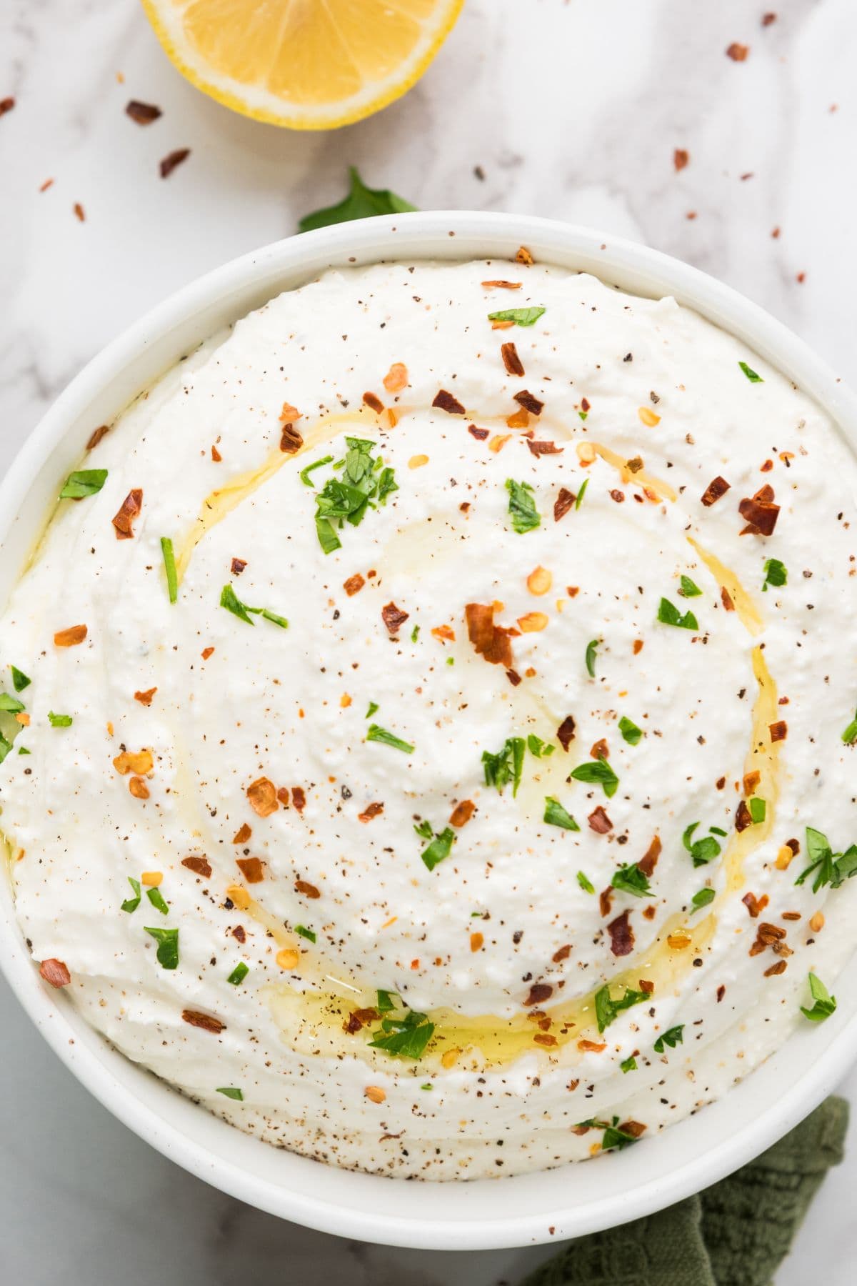Zesty lemony whipped feta dip served in a bowl, garnished with herbs and a drizzle of olive oil.