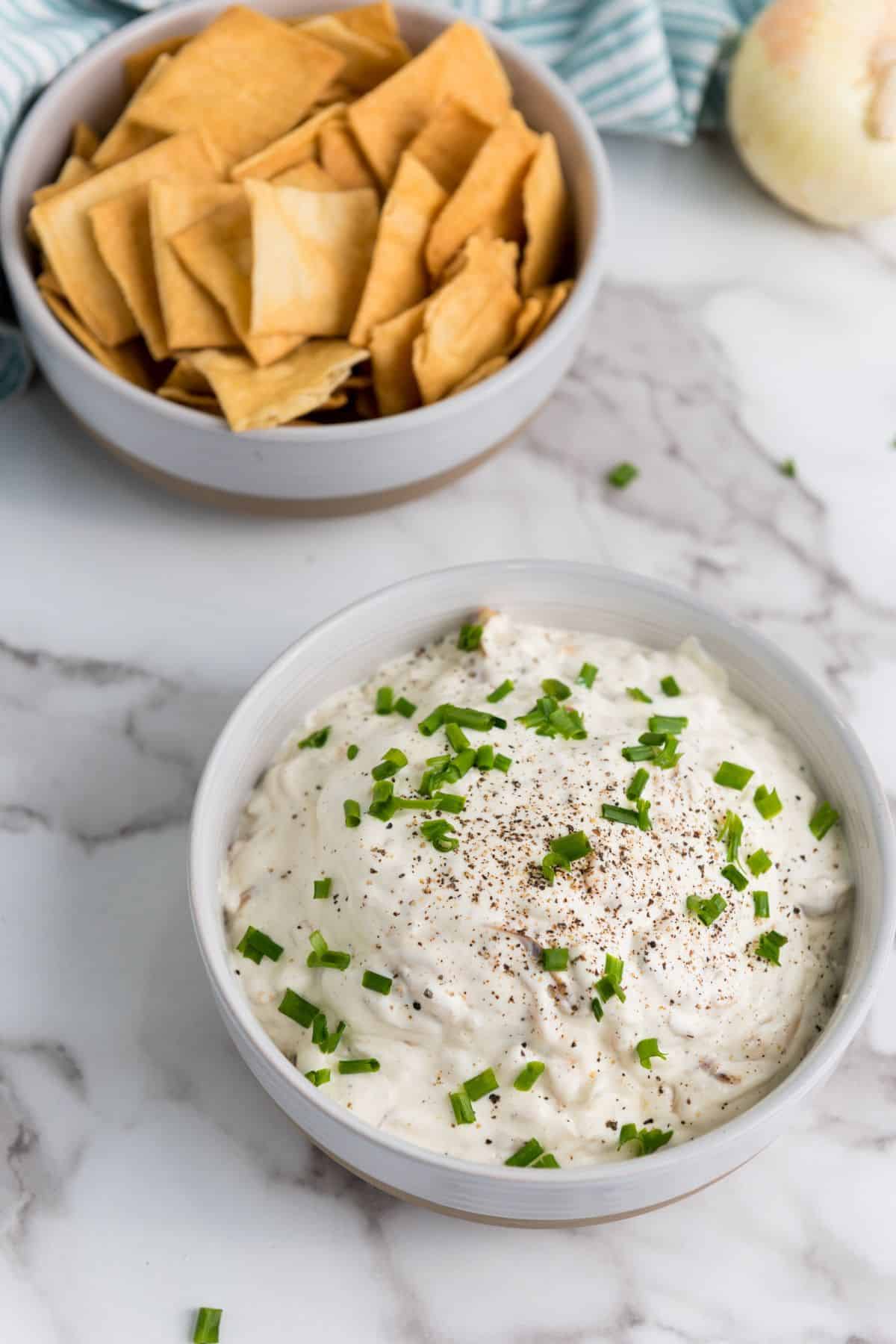 Caramelized onion dip served in a bowl with crackers on the side.
