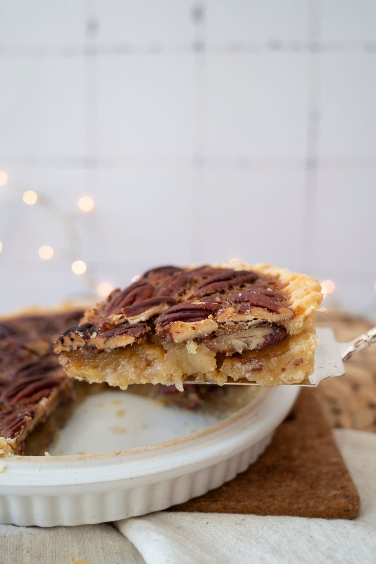 A slice of pie being lifted from a serving dish, showing the gooey filling and flaky crust.