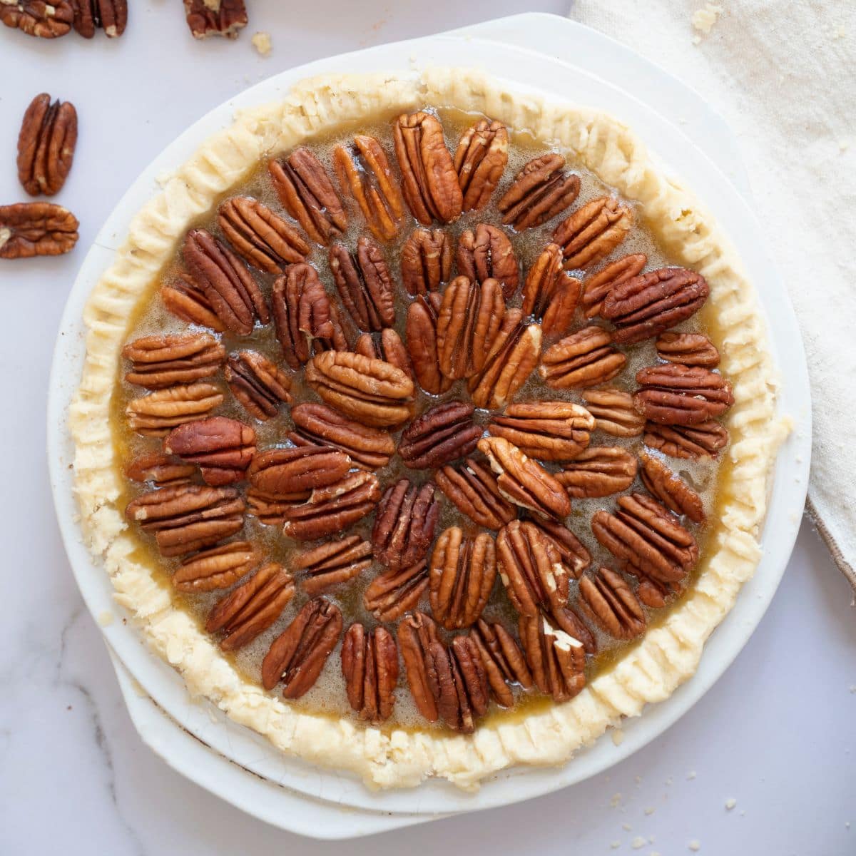 A whole pie in a serving dish, topped with pecans arranged on the surface.
