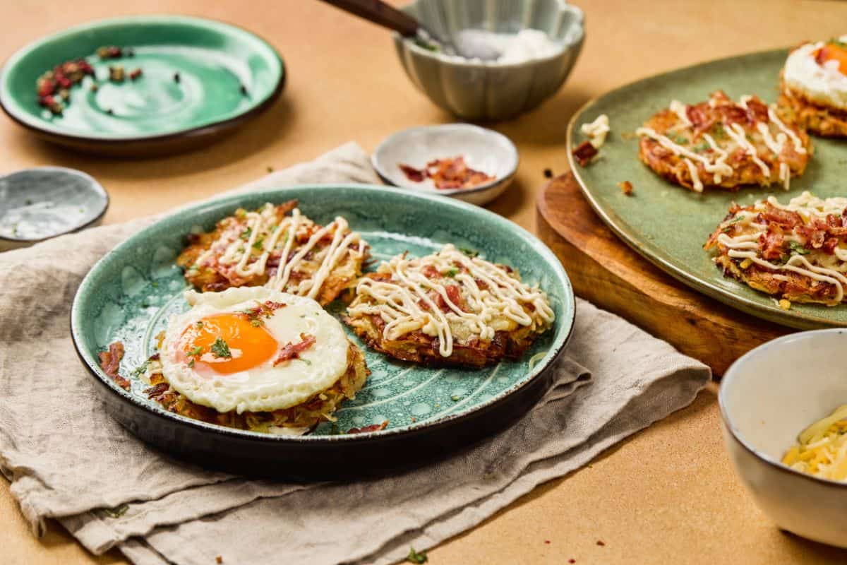 A sunny side up egg surrounded by fully loaded hashbrowns with melted cheddar, crispy bacon, green onions, and a drizzle of sour cream on a plate.