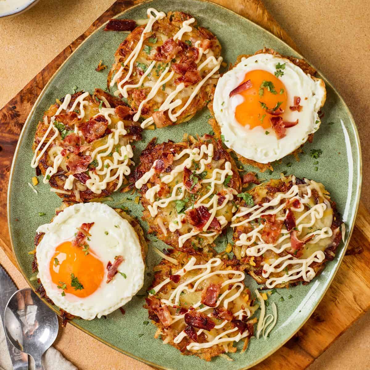 A sunny side up egg surrounded by fully loaded hashbrowns with melted cheddar, crispy bacon, green onions, and a drizzle of sour cream on a plate.