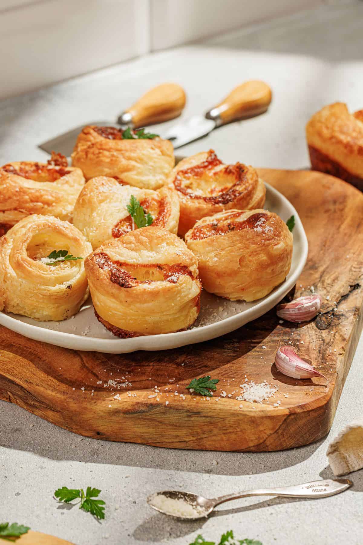 Plate of golden cheesy garlic cruffins on a rustic wooden serving board.