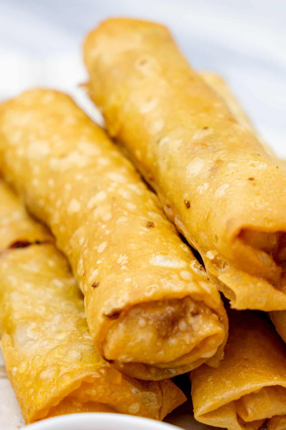 Close-up of stacked chicken and vegetable spring rolls on a plate.