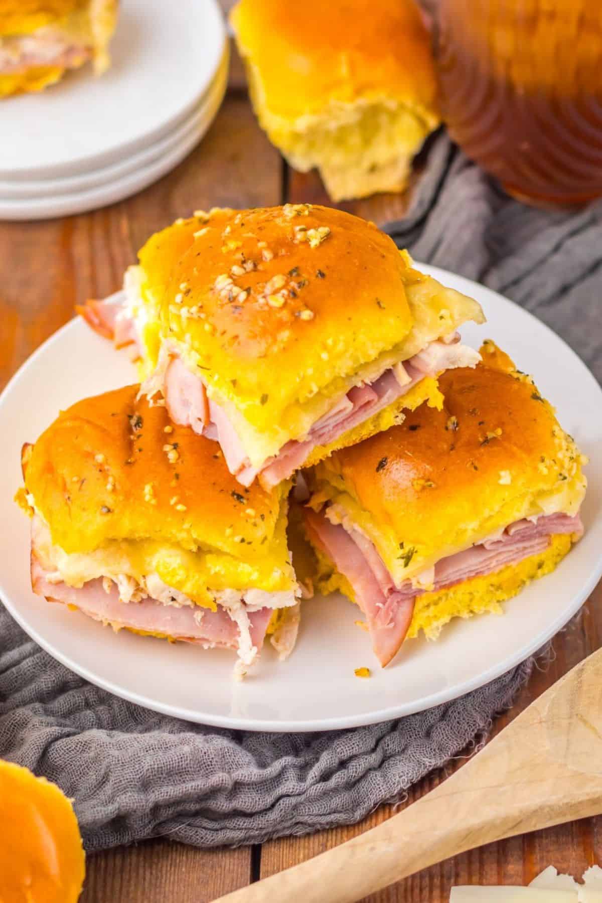 Chicken cordon bleu sliders on hawaiian rolls stacked on a plate.