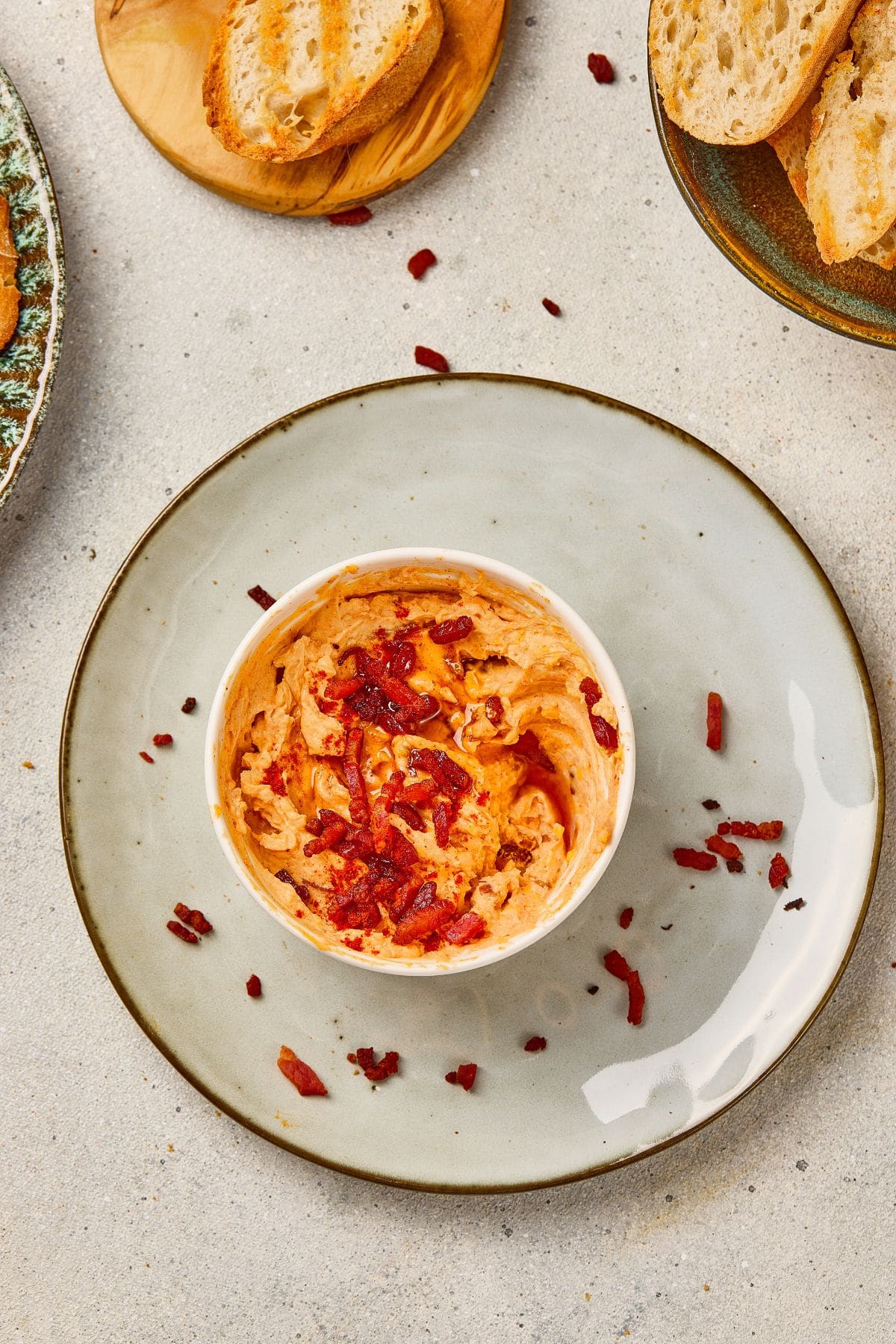 A bowl of maple bacon cheese dip on a plate, garnished with crumbled bacon bits.