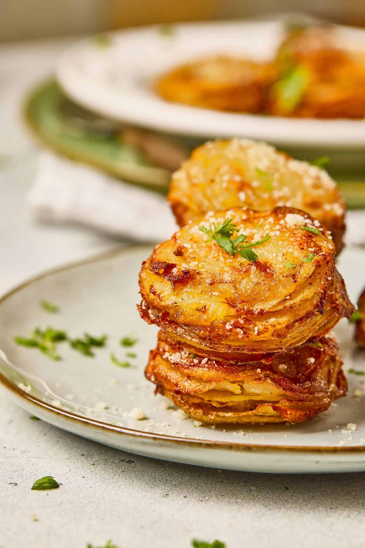 Close-up of parmesan garlic potato stacks on a plate, showing golden layers and crispy edges.