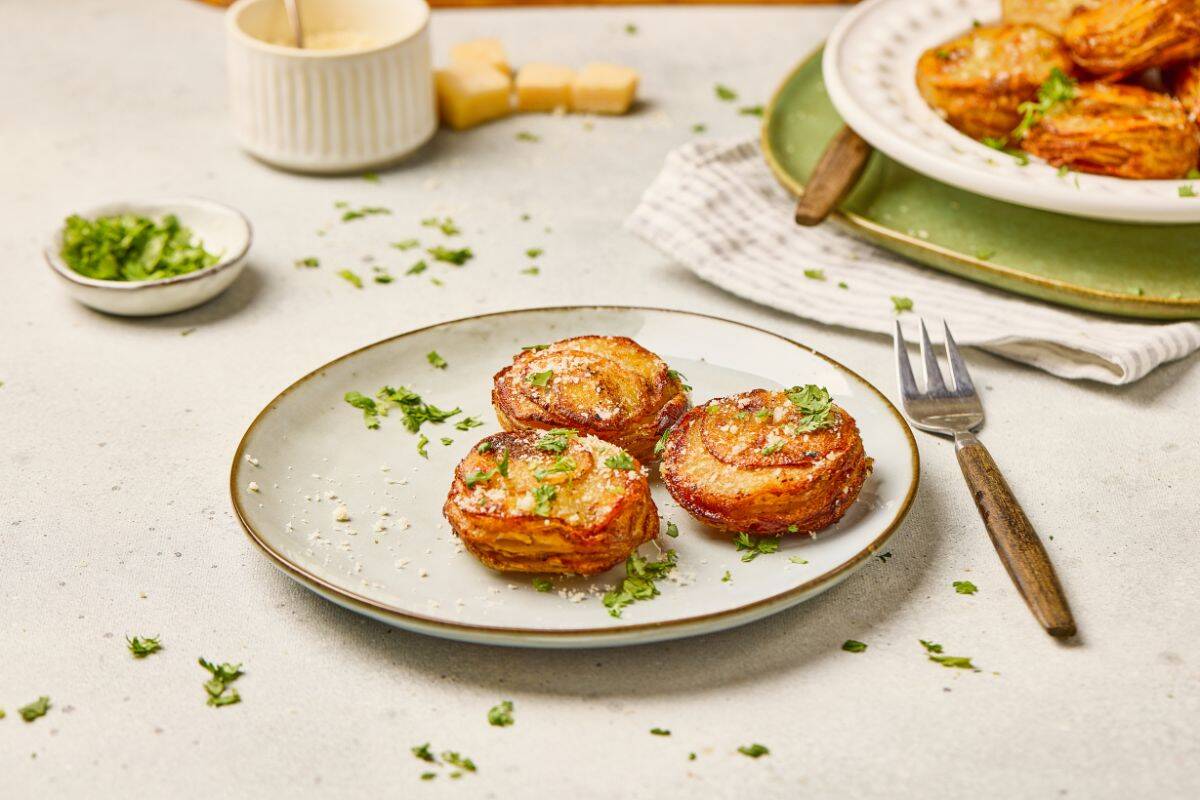 Plates with stacked parmesan garlic potato stacks, golden brown and garnished with fresh herbs.