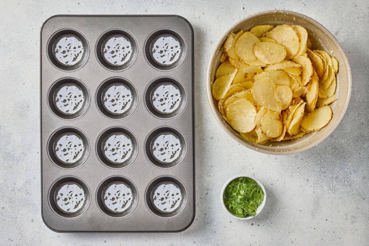 Baking tin filled with parmesan garlic potato stacks, with ingredients arranged on the side.