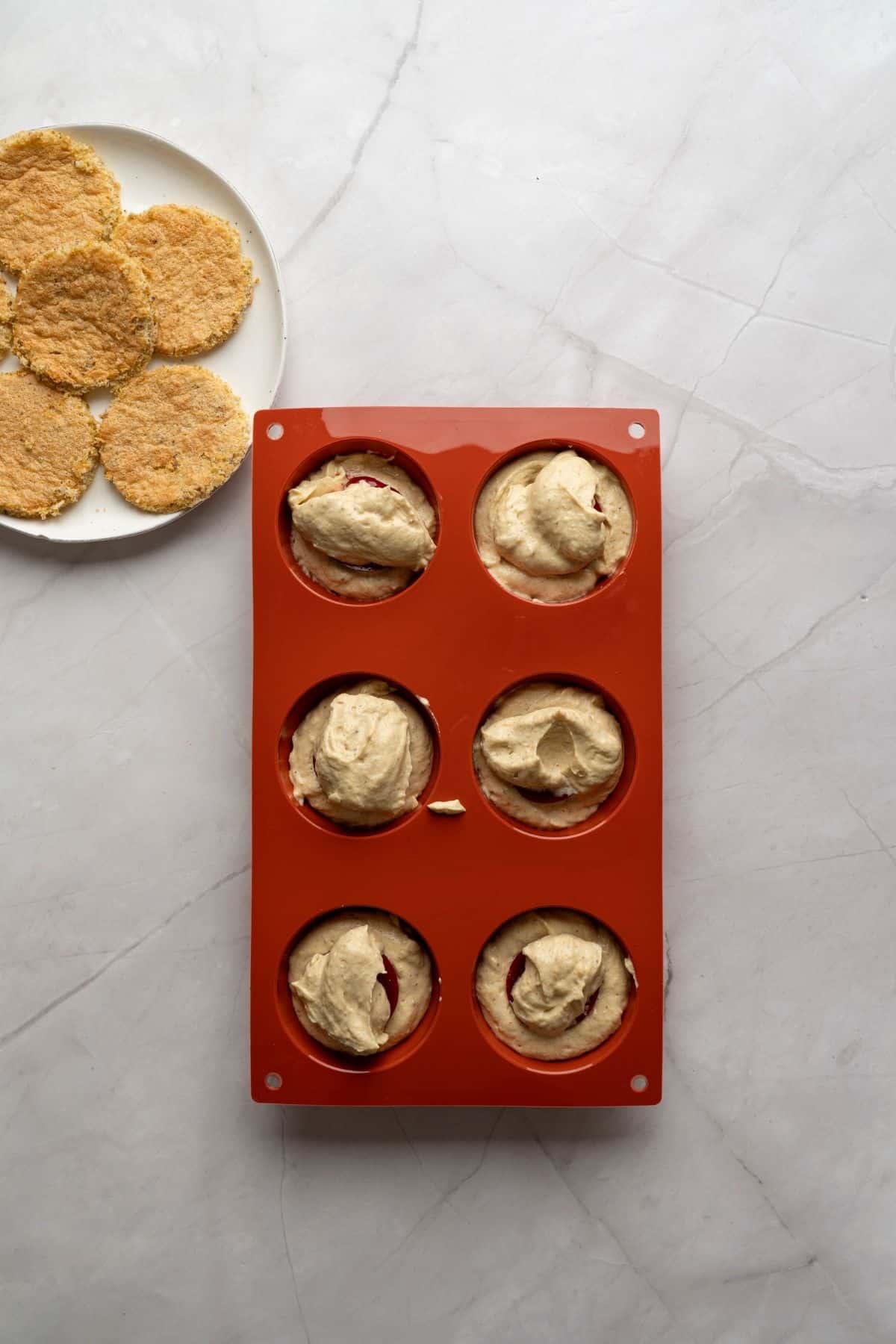 A cheesecake dome topped with white chocolate glaze, placed in a baking pan.