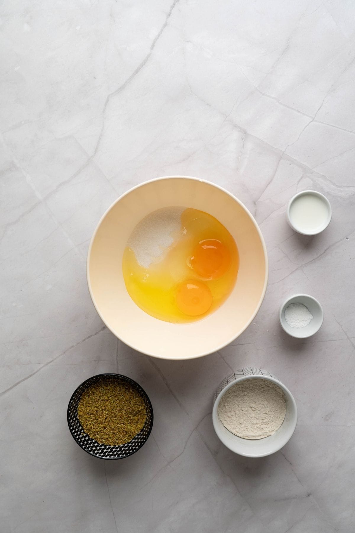 A medium bowl with ingredients, surrounded by other ingredients on the surface.