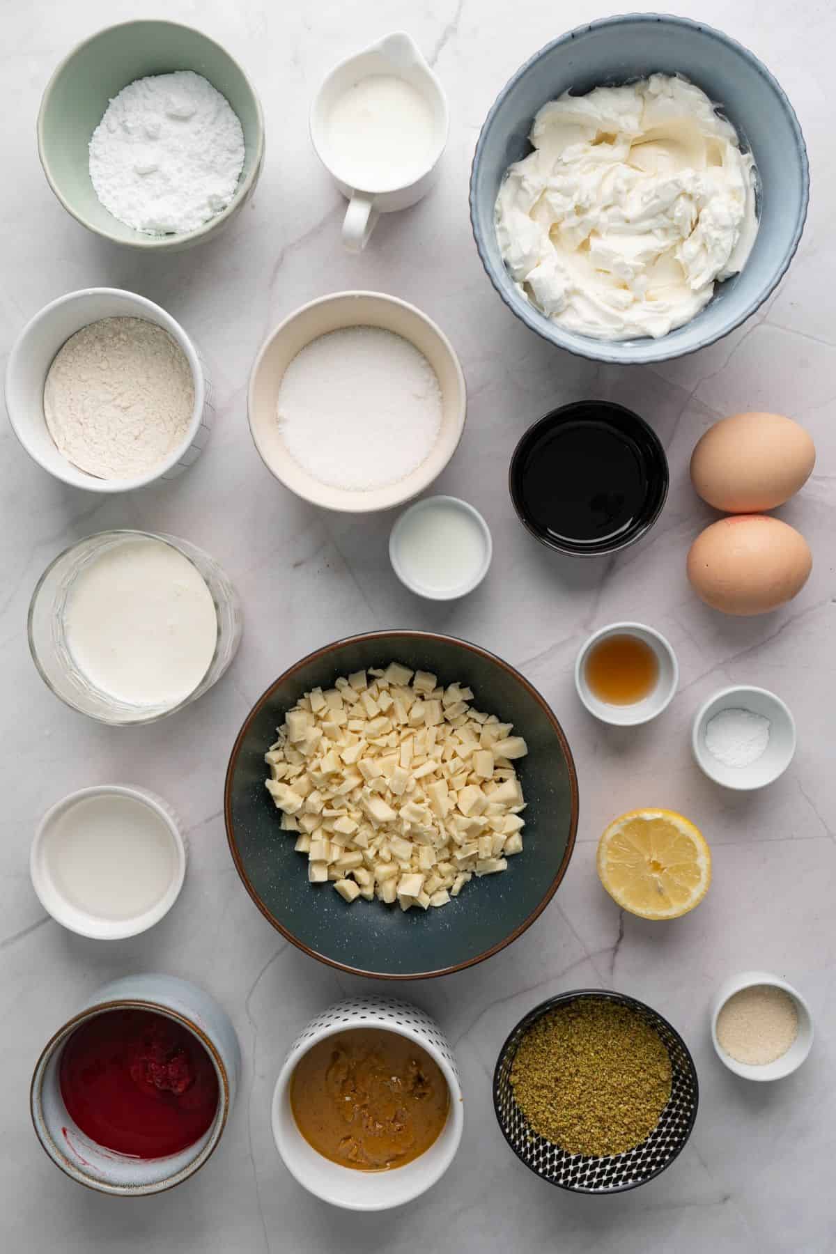 Ingredients for making pistachio raspberry mini cheesecake domes arranged neatly on a surface.