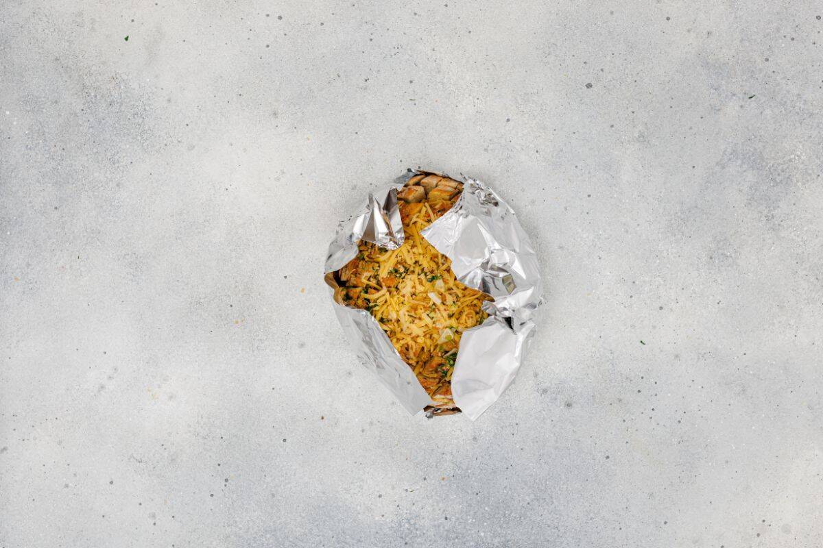 Cheesy pull-apart garlic bread stuffed with butter, garlic, and grated cheese, garnished with parsley, wrapped in foil and ready to bake.