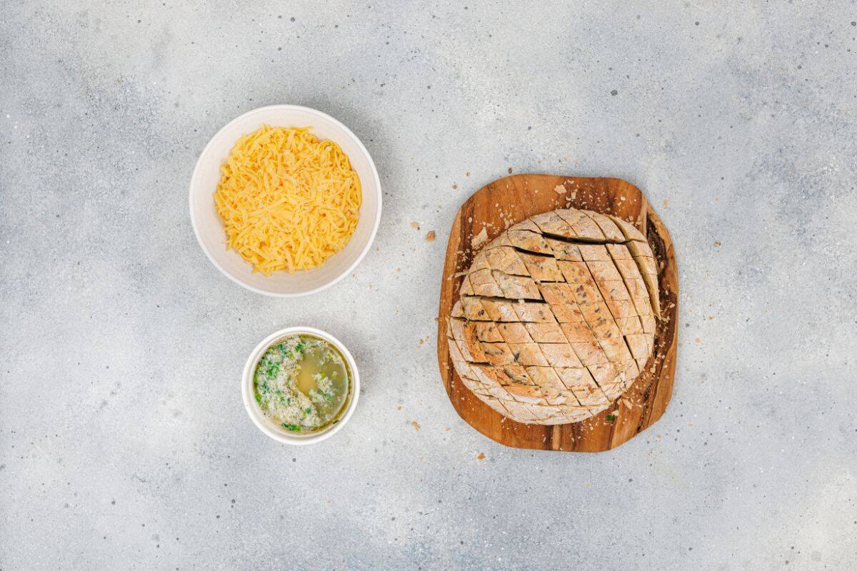Ingredients for cheesy pull-apart garlic bread neatly arranged on a surface.