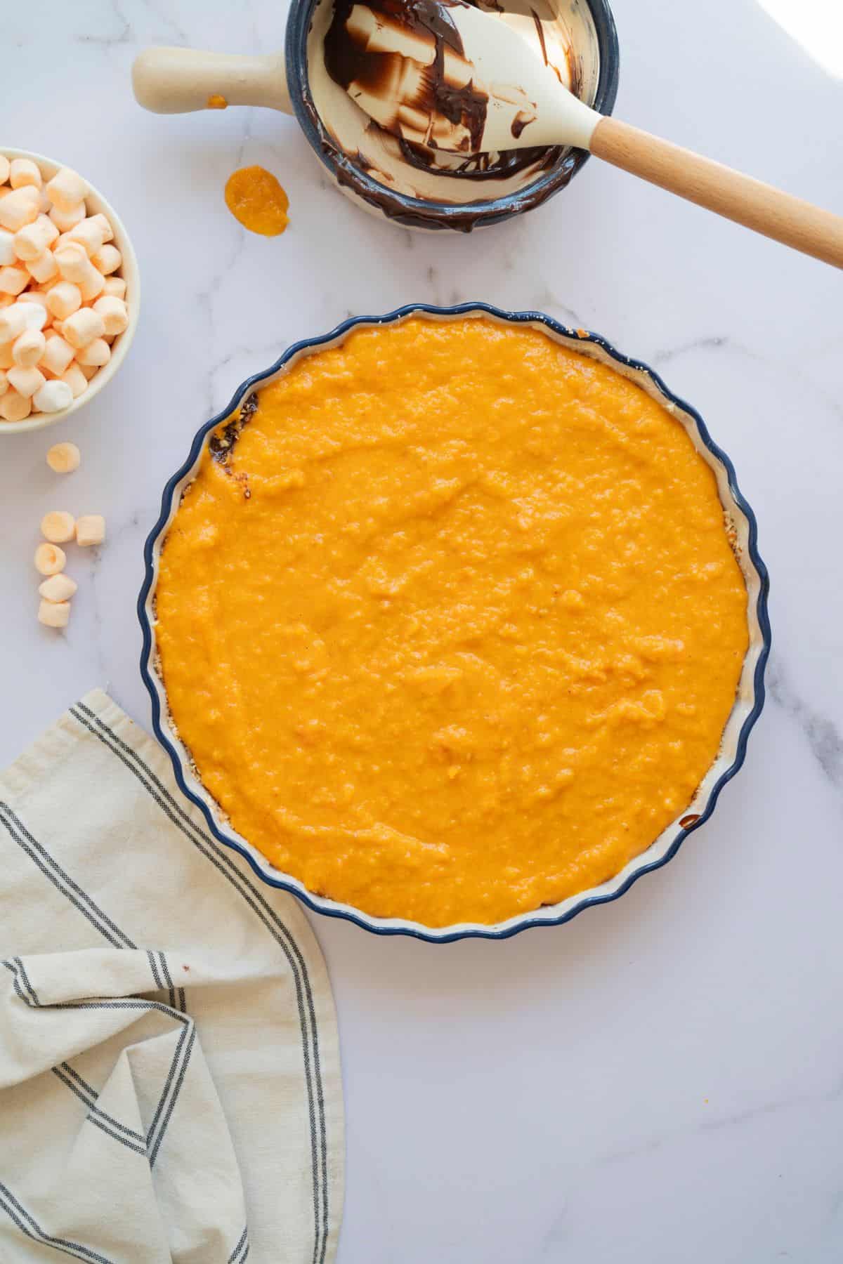 An unbaked sweet potato pie with the filling ready in the crust, set in a pie pan.