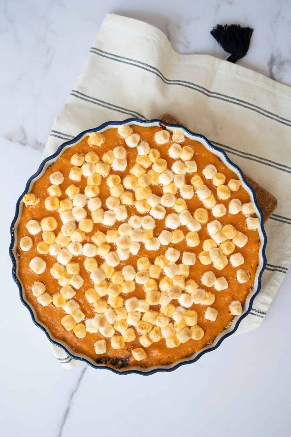 A whole sweet potato pie topped with golden, toasted marshmallows.