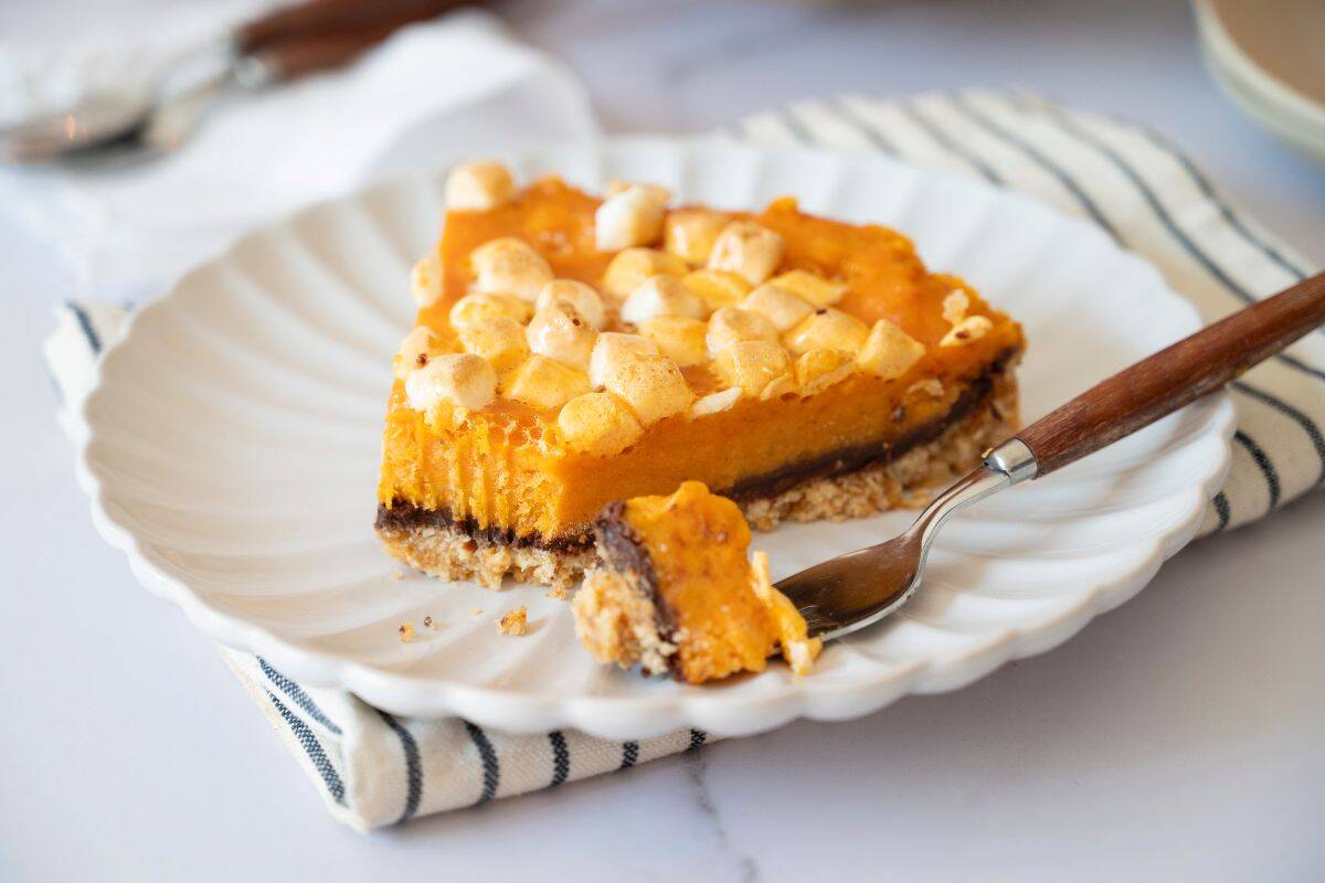 A close-up of a sliced sweet potato pie on a plate with a fork beside it.