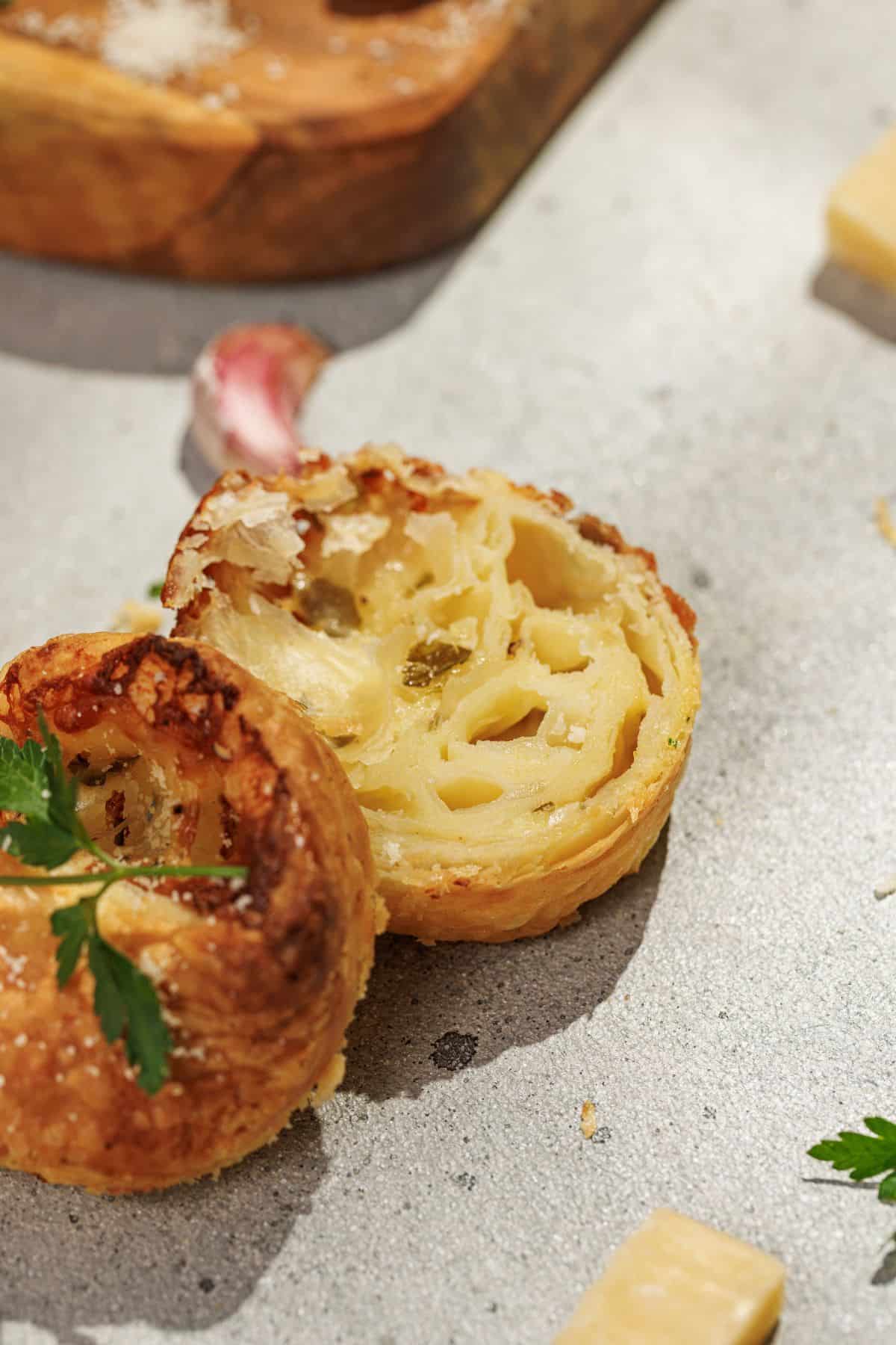 Cheesy garlic cruffins sliced to reveal their soft, layered interior placed in surface.