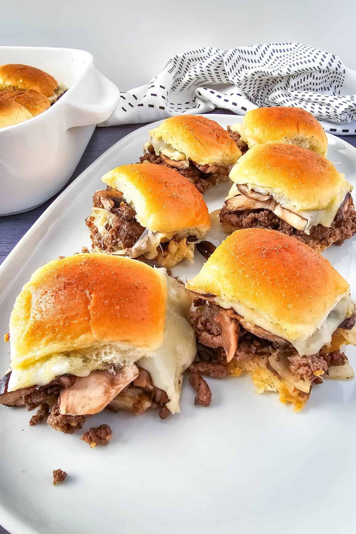 Savory mushroom sliders arranged on a plate, showcasing melted cheese and toasted buns.