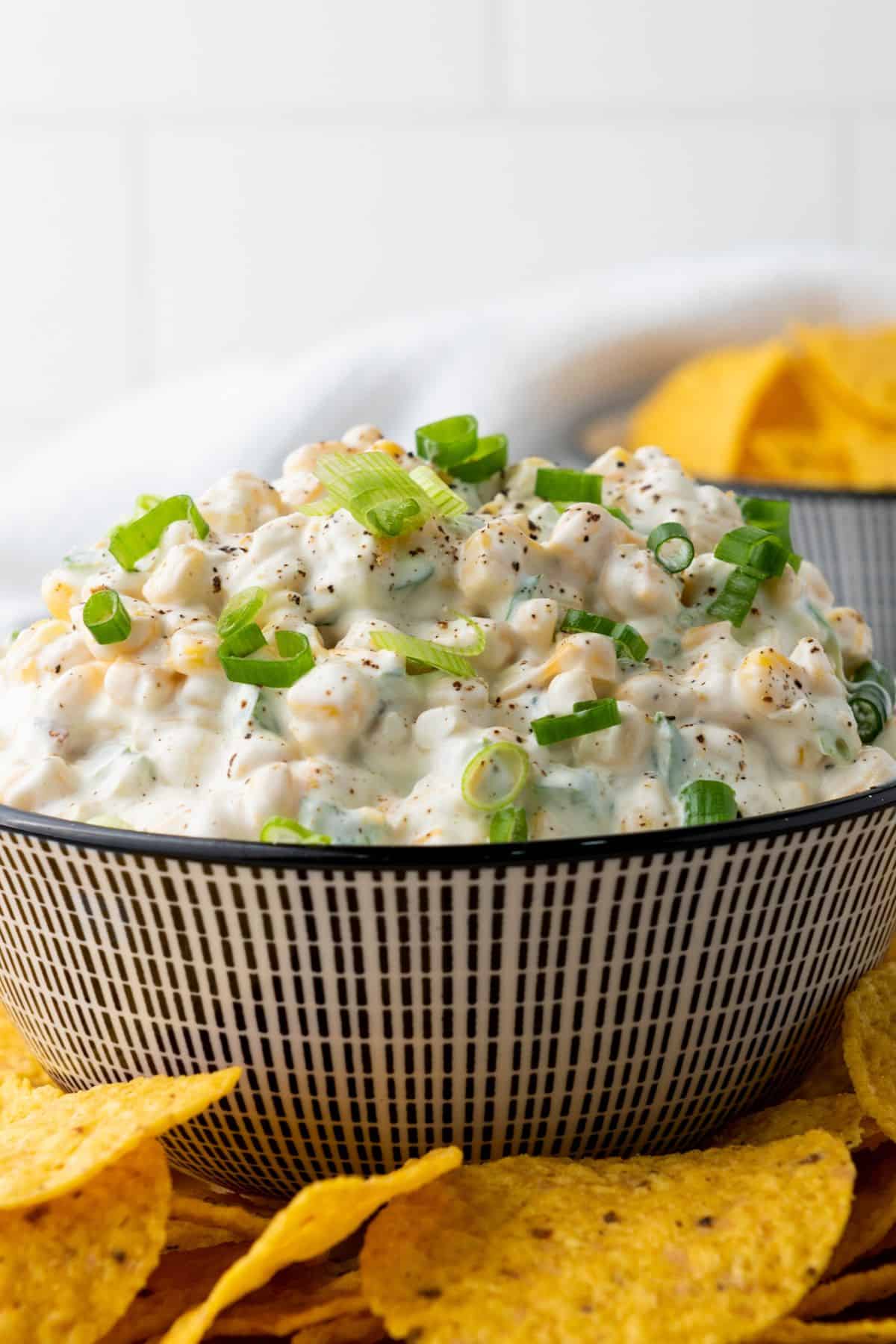 Creamy corn dip served in a bowl with crispy tortilla chips on the side for dipping.