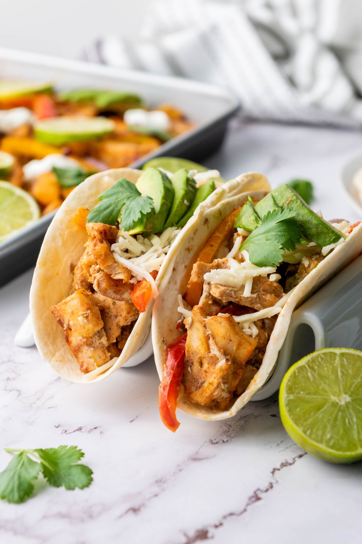 Close-up of chicken and vegetables from a sheet pan wrapped in a tortilla.