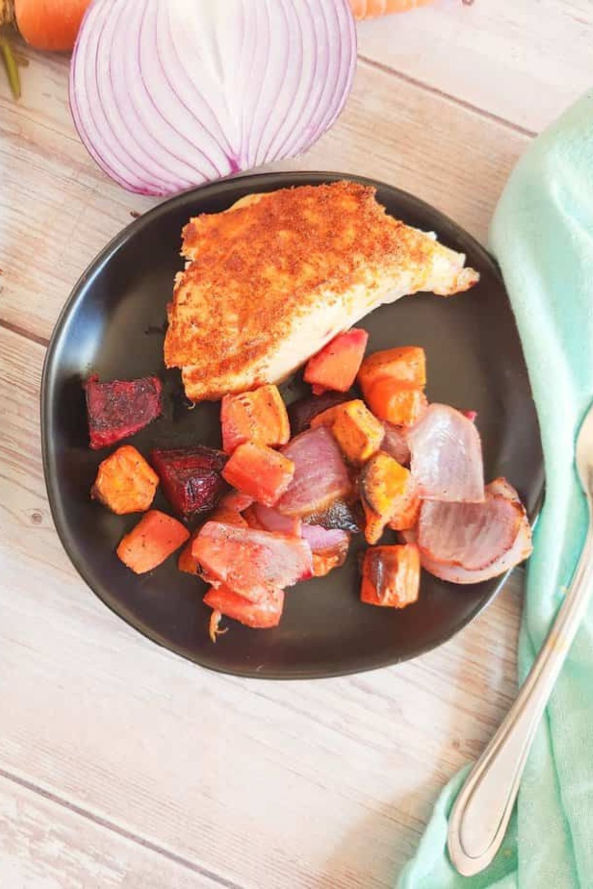 Roasted chicken served on a plate with a mix of roasted vegetables.