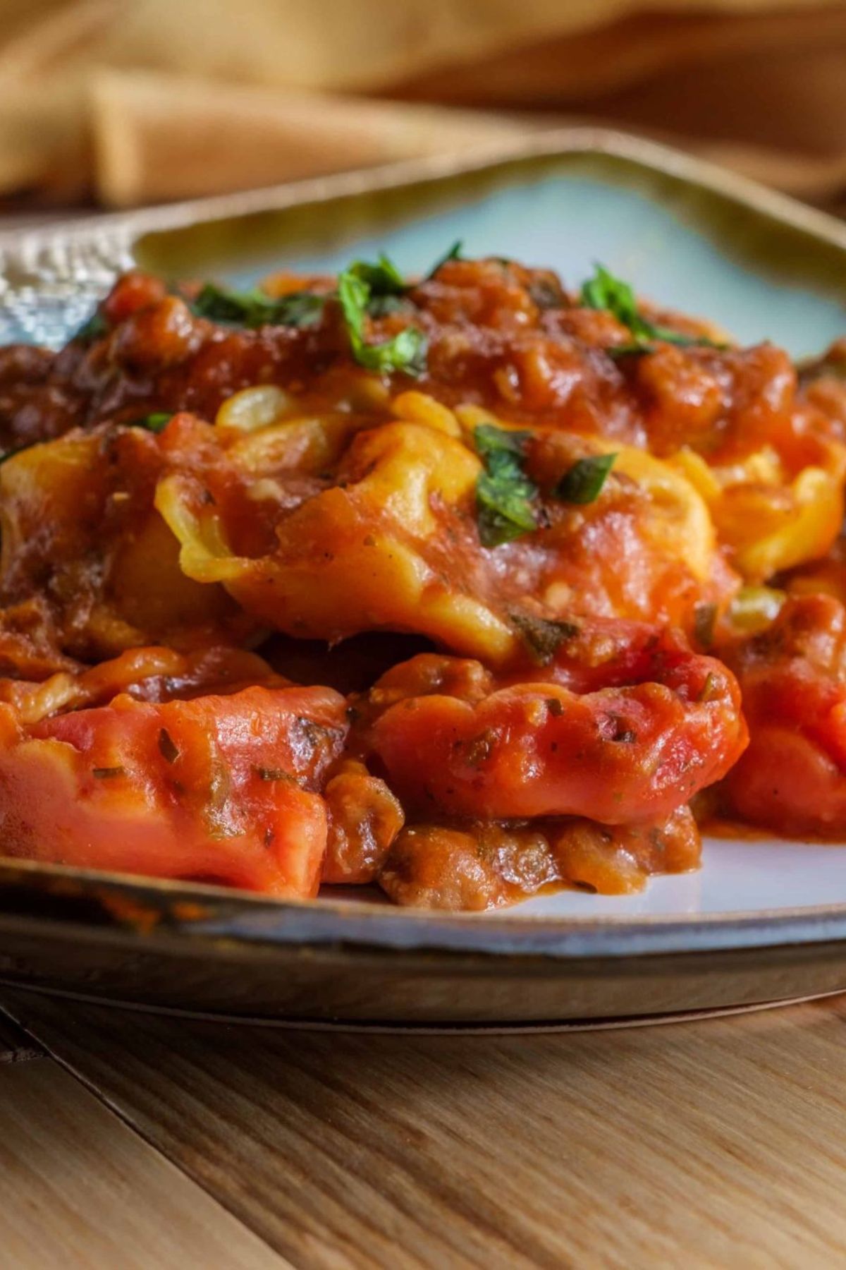Close-up of cheesy baked tortellini served on a plate.