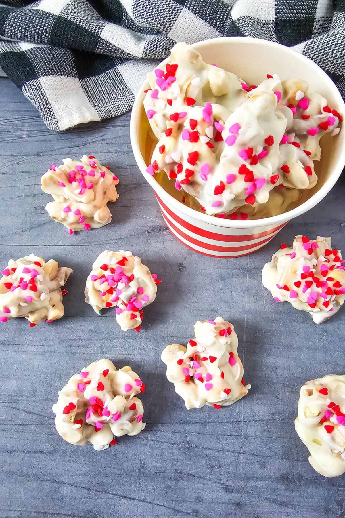 White chocolate-covered popcorn decorated with red, pink, and white heart-shaped sprinkles.