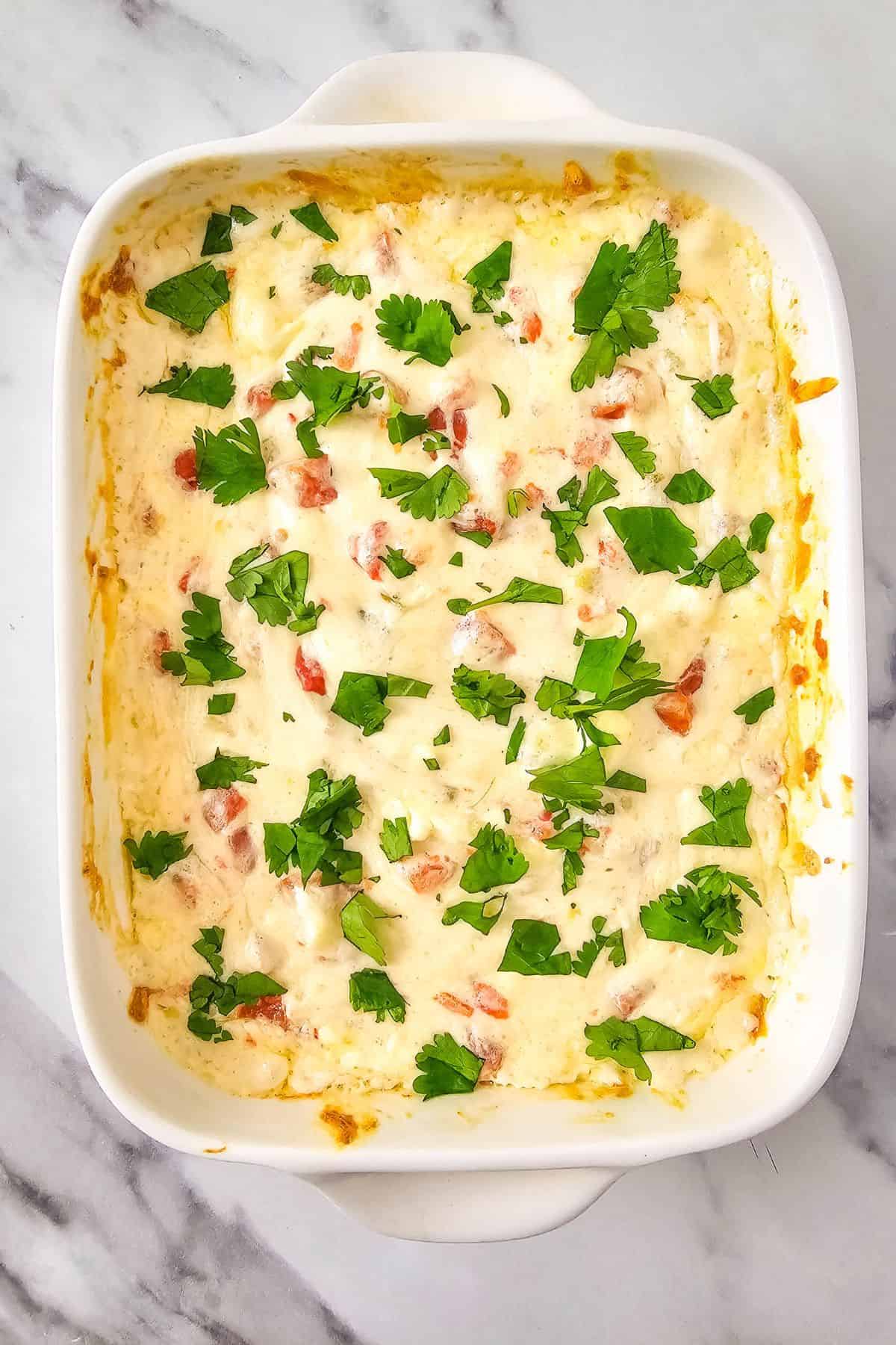Creamy baked chicken casserole topped with cheese and fresh cilantro.