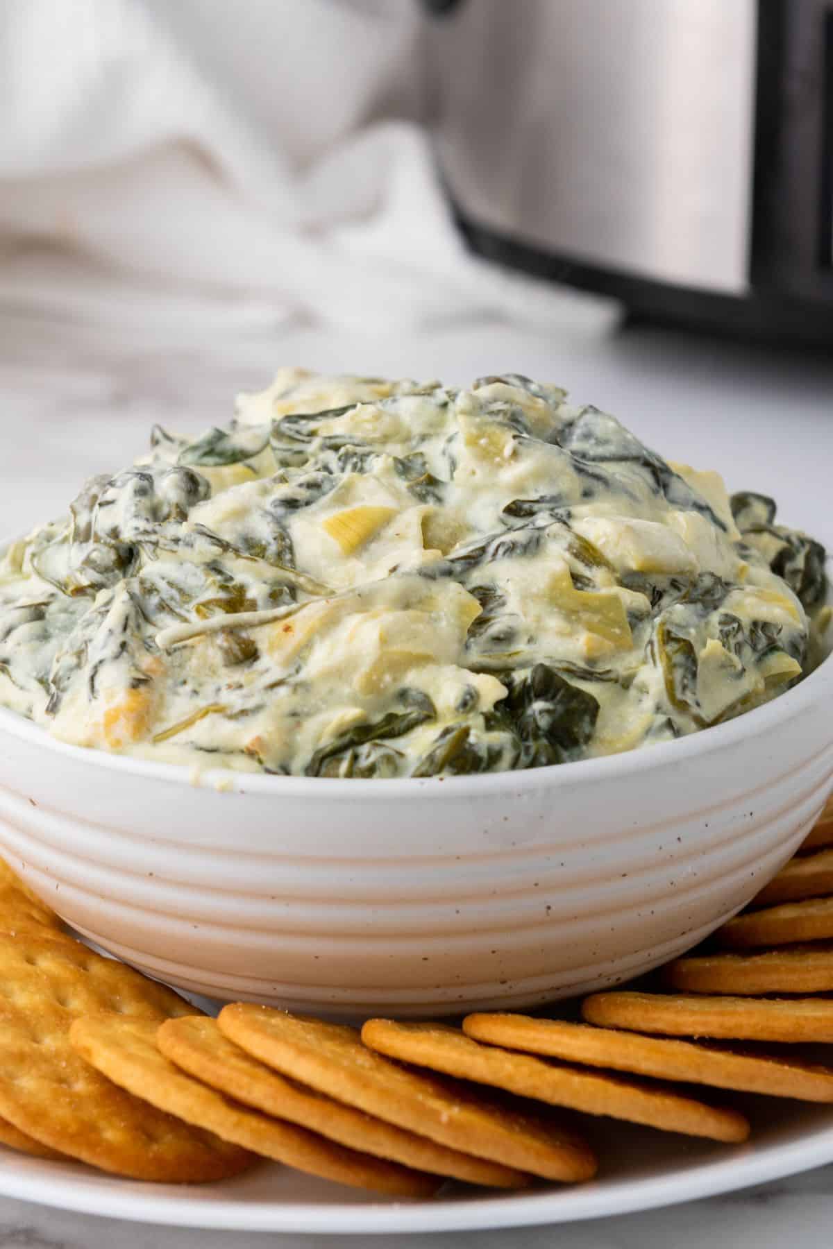 Delicious homemade spinach dip with cheese served with crispy crackers. Perfect for parties and gatherings.