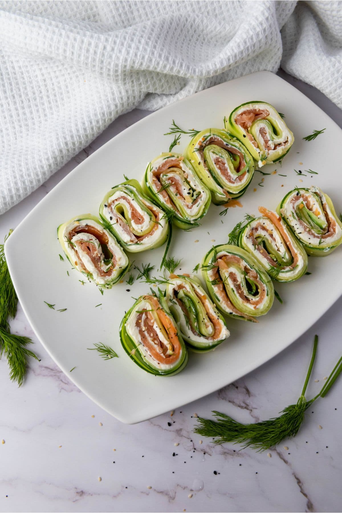Delicious cucumber wraps filled with smoked salmon and cream cheese, garnished with fresh herbs.