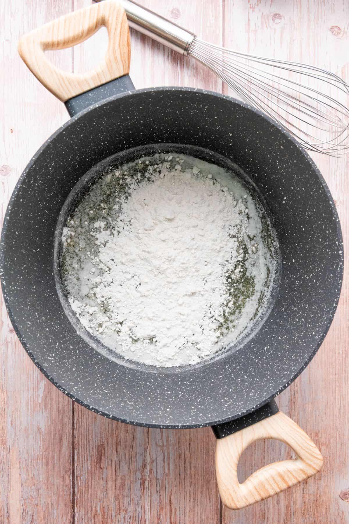 A saucepan filled with flour, ready for making a roux or sauce.