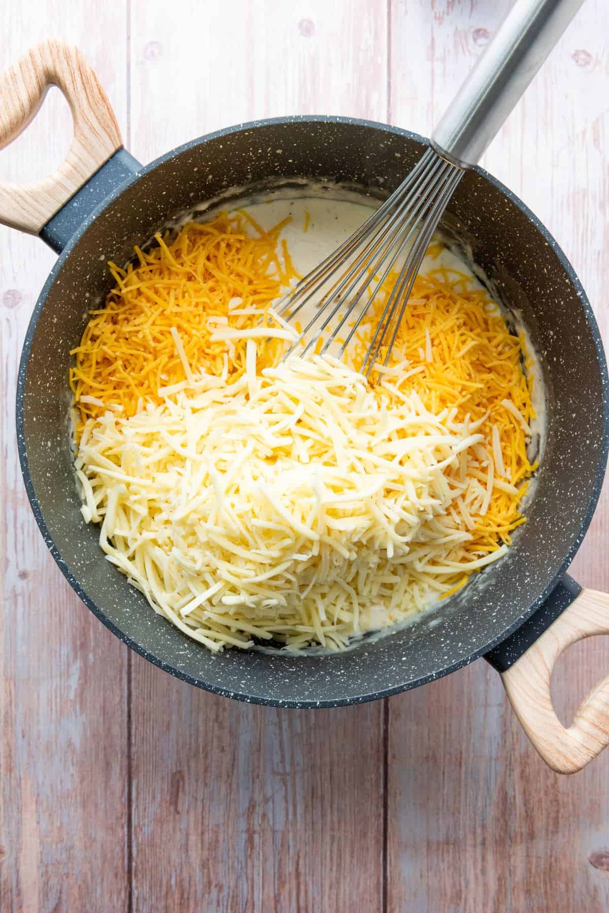 Ingredients being stirred in a saucepan with a whisk resting on the edge.