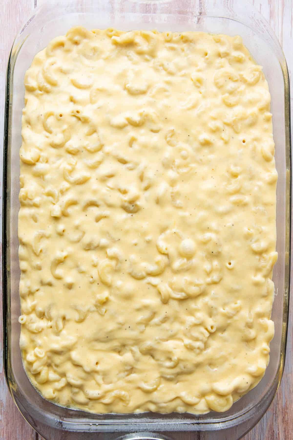 Homemade creamy macaroni and cheese ready to bake in a glass baking dish.